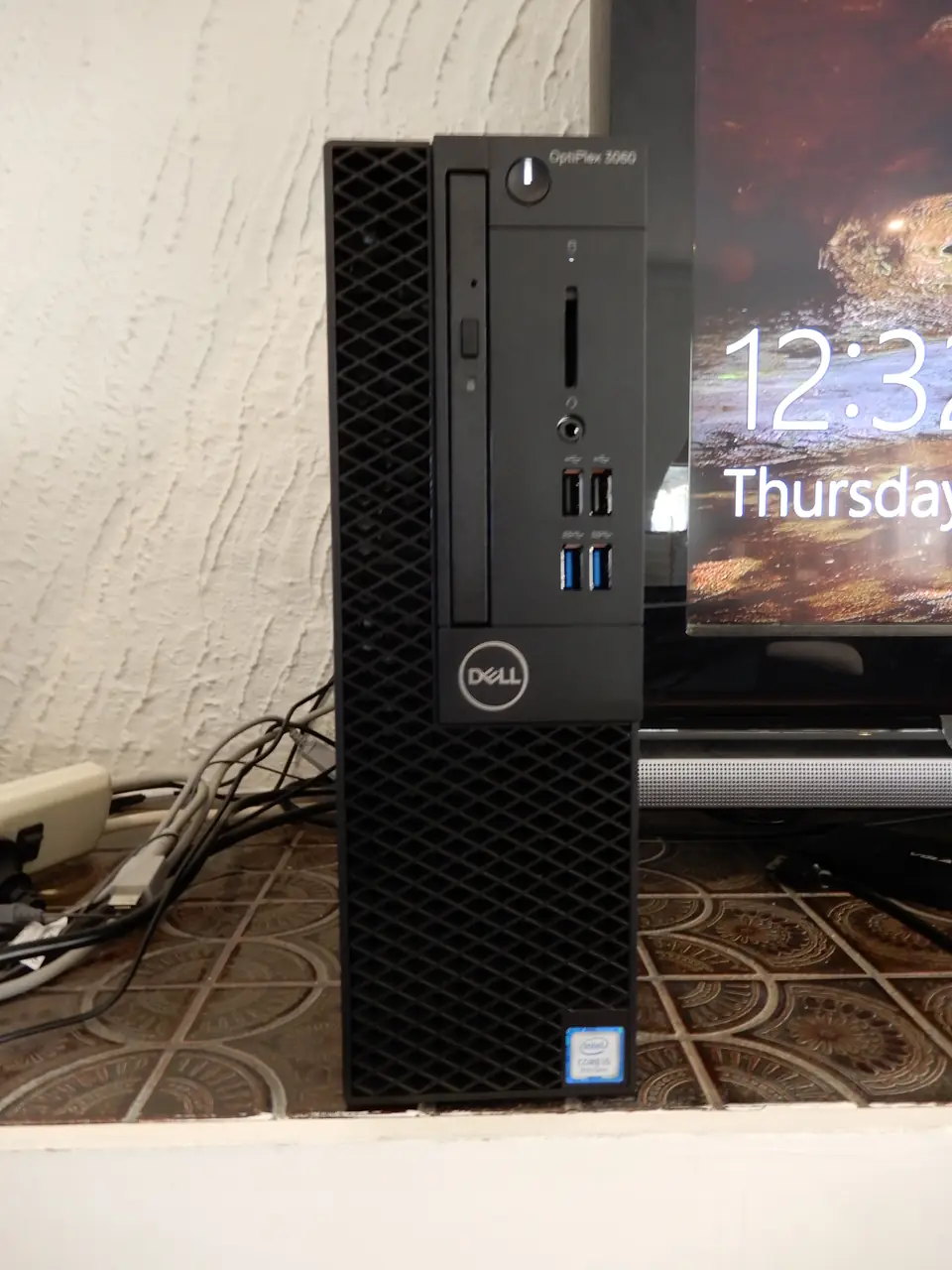 Front of a Dell OptiPlex 3060 small-form-factor desktop standing beside a monitor.