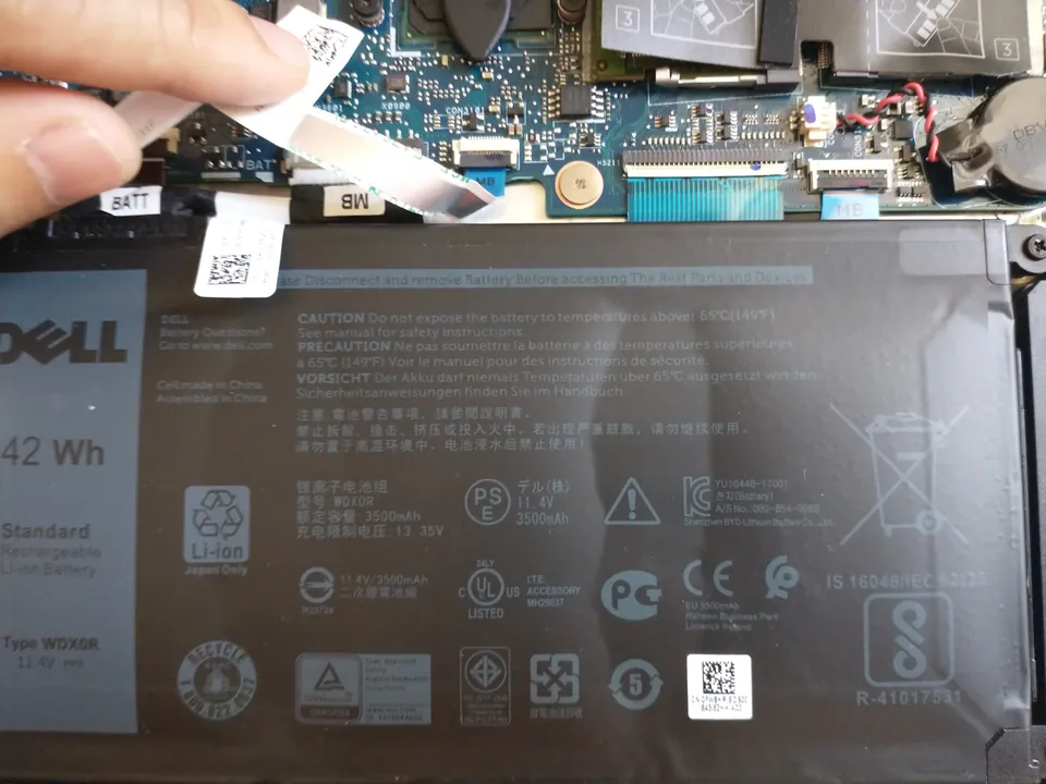 Internal Dell 42 Wh laptop battery alongside motherboard components and cables.
