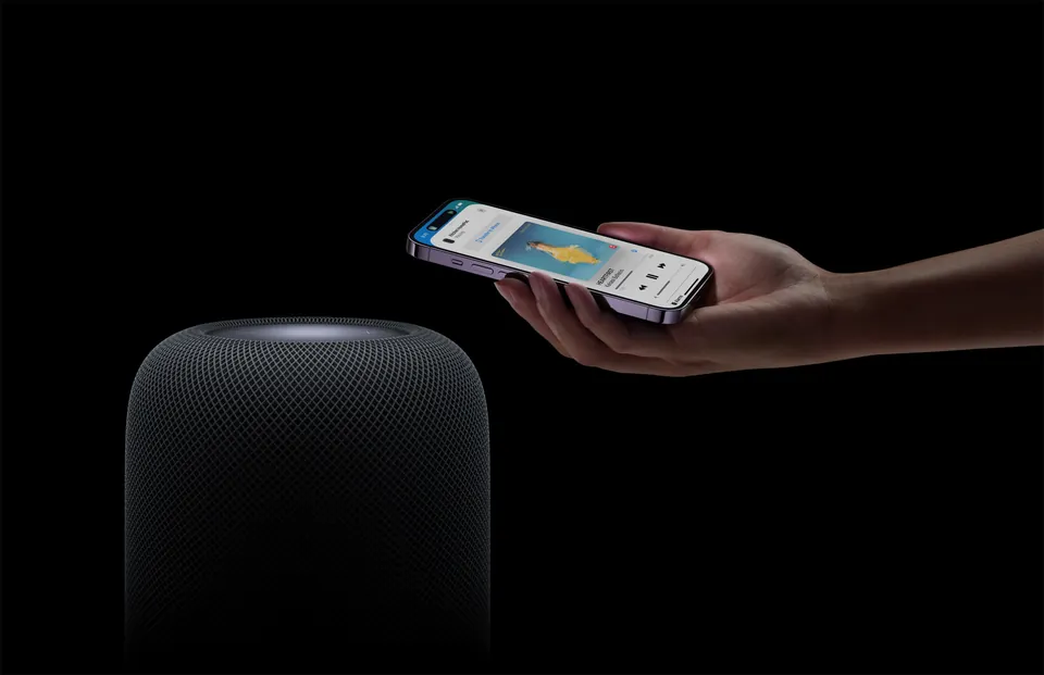 A person holding an iPhone close to a second-generation HomePod for audio handoff